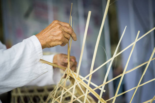 An old man using his hands to weave bamboo 