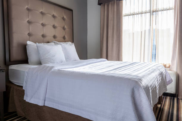 A queen sized bed covered in white bamboo sheets   