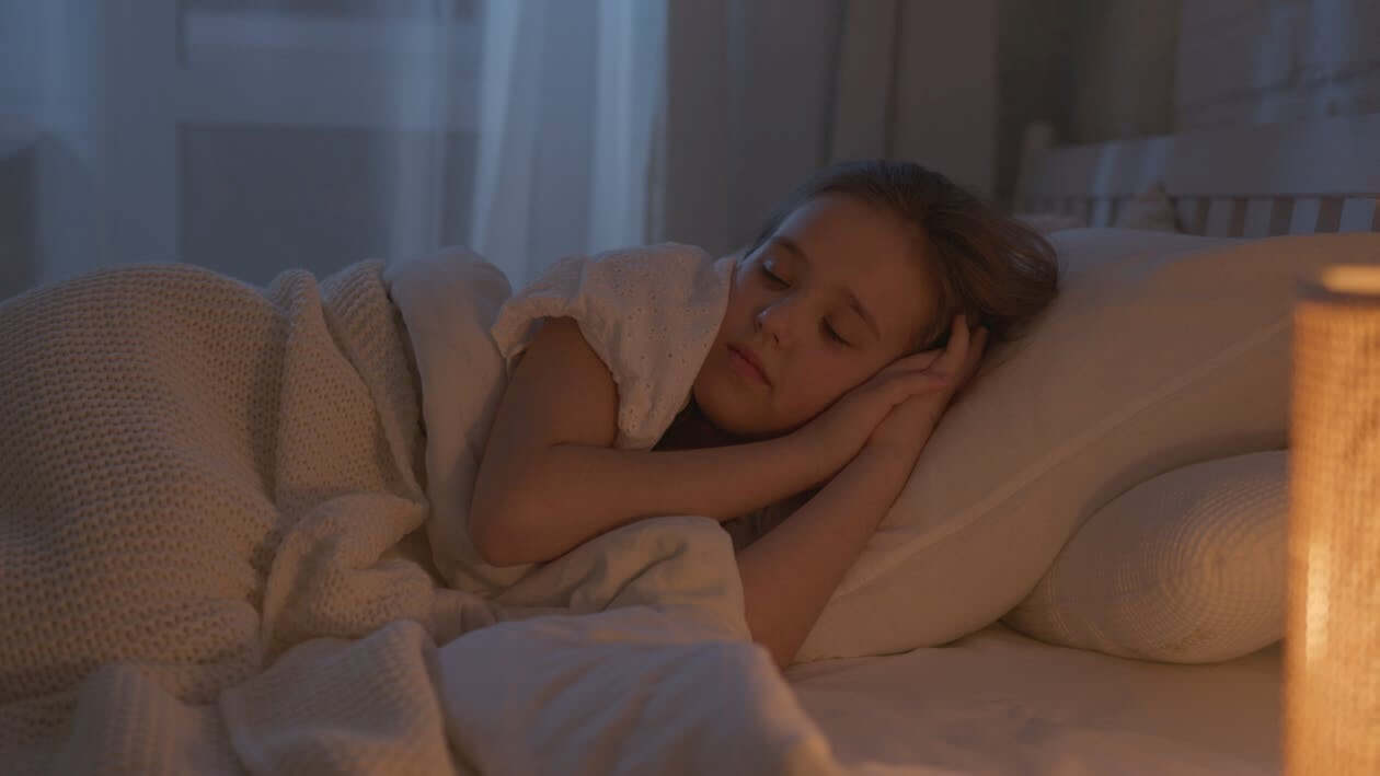 a girl sleeping peacefully on a bamboo sheet