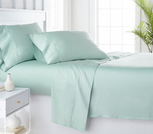 Set of 100% organic bamboo sheets laid across the bed in the color green
